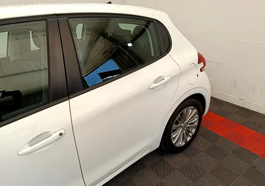 Vue côté droit arrière d'une Peugeot 208 Puretech 82 Signature blanche avec jante alliage et poignée de porte visible.
