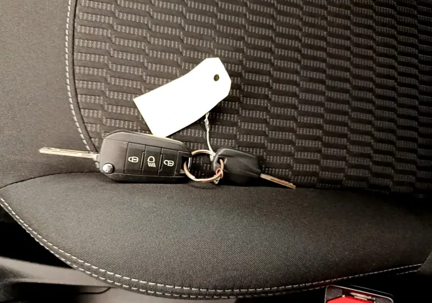 Clé de contact posée sur le siège avant en tissu noir de la Peugeot 208 Puretech 82 Signature blanche de 2019.