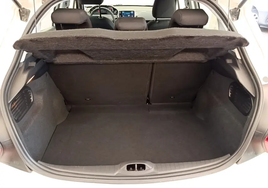 Coffre ouvert d'une Peugeot 208 blanche vue de l'arrière, montrant l'espace de chargement et les sièges arrière.