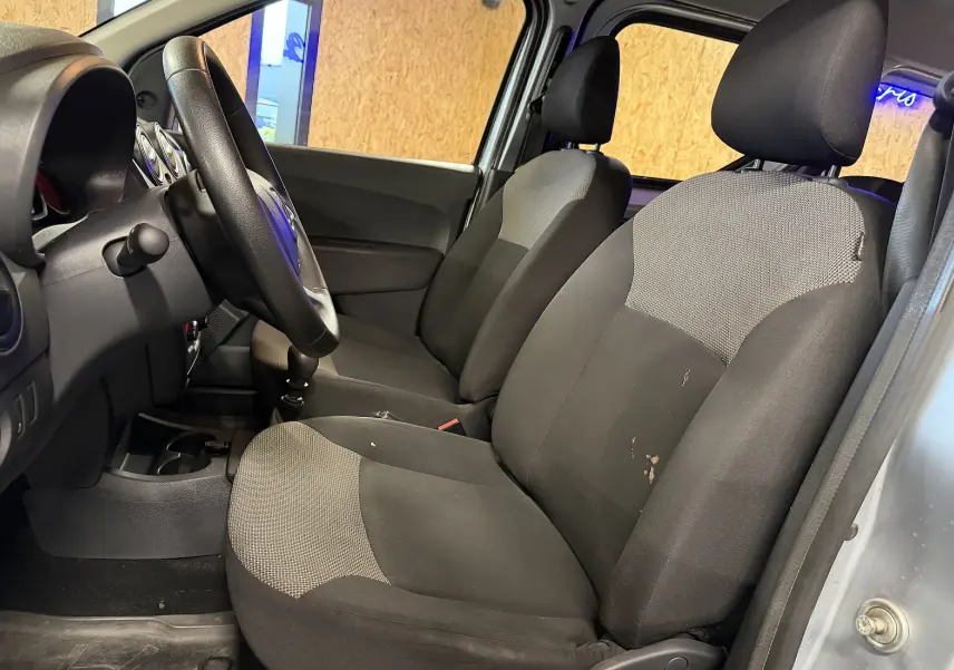 Vue intérieure côté gauche du Dacia Dokker gris 2019, montrant les sièges avant en tissu bicolore et le volant multifonctions.