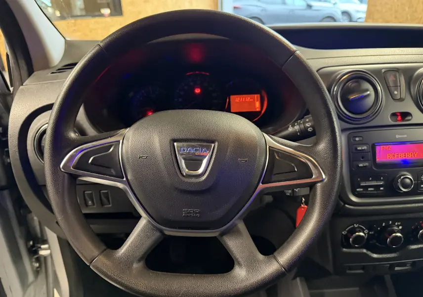 Vue rapprochée du volant multifonctions noir du Dacia Dokker 2019 avec tableau de bord et console centrale visibles.