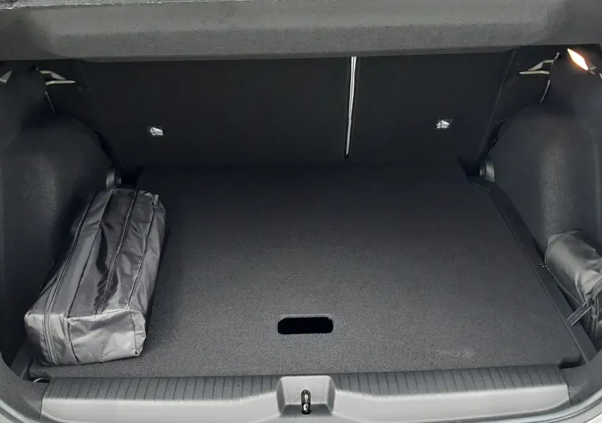 Coffre ouvert vu de l'arrière d'une Citroën C3 Aircross hybride gris avec toit noir, montrant un intérieur de coffre spacieux et un sac noir.