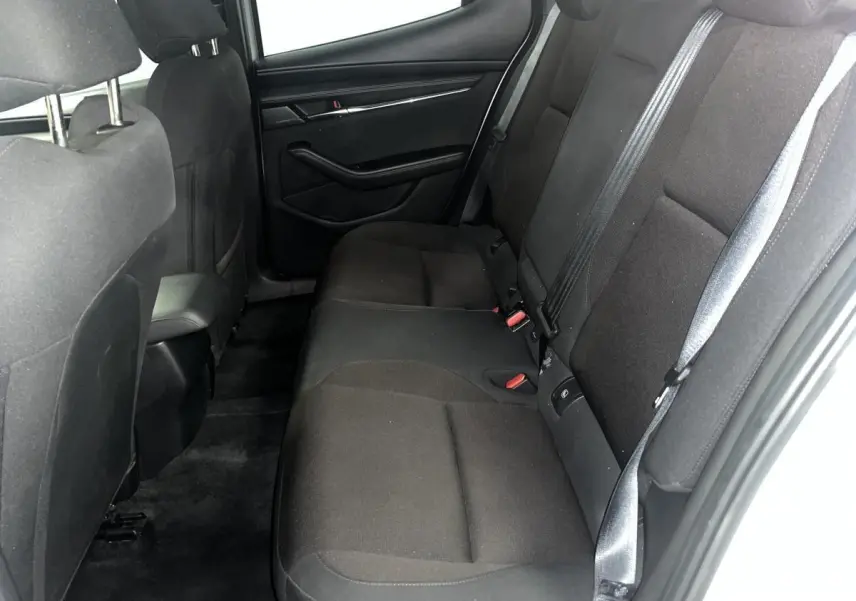 Vue latérale droite de l'intérieur arrière de la Mazda3 2023 avec sièges tissu noir et ceintures de sécurité grises.