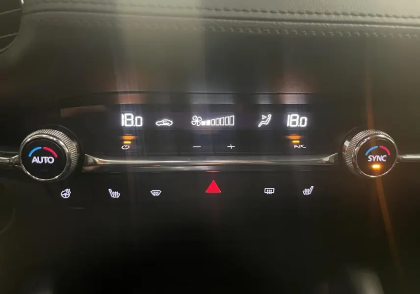 Gros plan sur la console centrale du Mazda3 gris 2023, affichant la climatisation automatique réglée à 18°C.