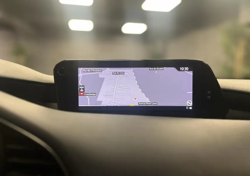 Écran central du système de navigation de la Mazda3 2023 affichant une carte routière en intérieur noir.