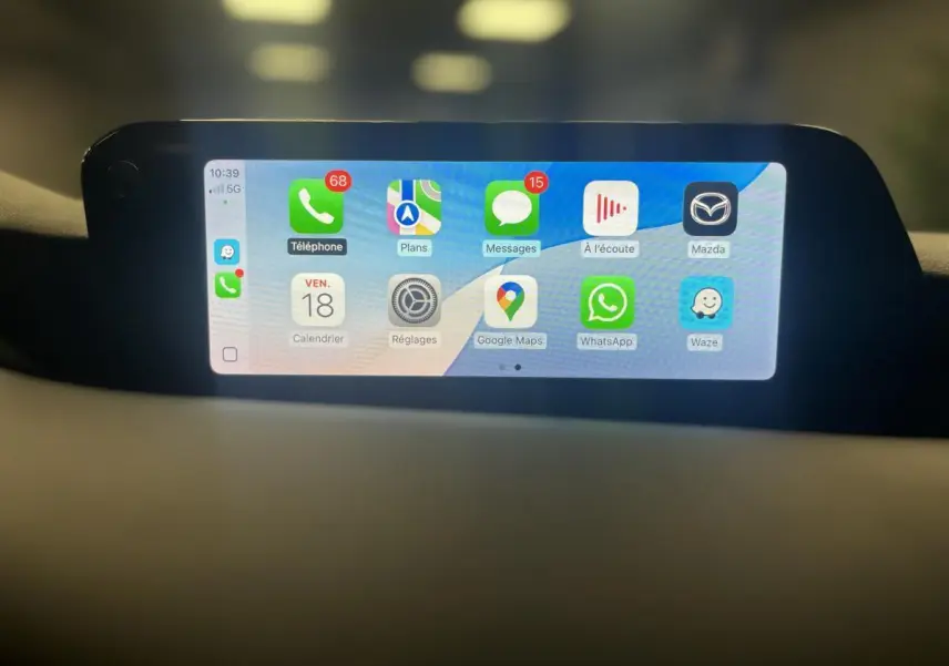Écran central tactile affichant Apple CarPlay dans l'habitacle d'une Mazda3 gris 2023, vue de face.