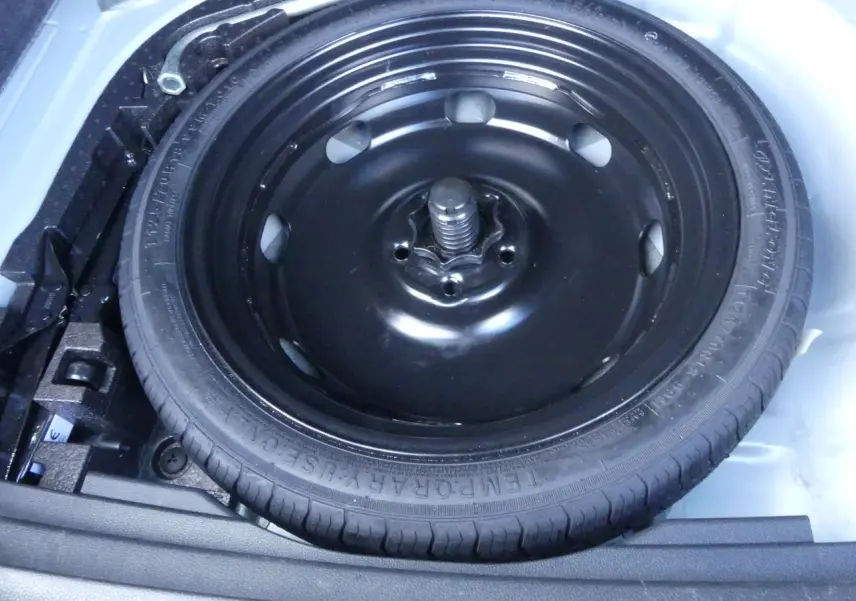 Gros plan sur la roue de secours noire dans le coffre d'un SEAT Ateca gris clair 2023.