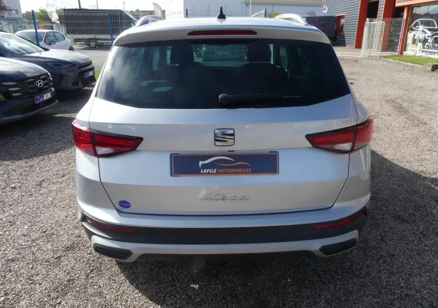 Vue arrière d'un SEAT Ateca gris clair 2023 avec feux arrière LED et hayon électrique sur un parking.