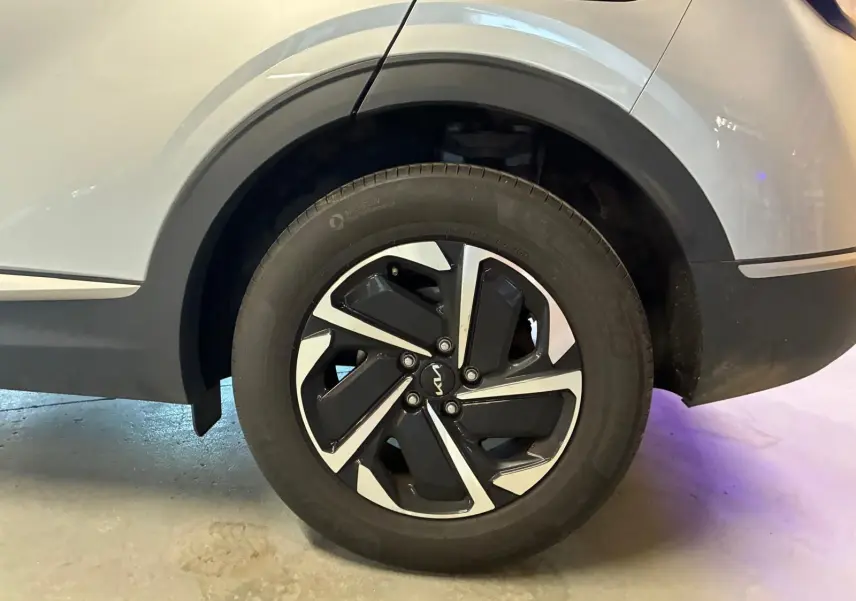 Gros plan sur la roue arrière droite du KIA Sportage gris 2024, mettant en valeur la jante noire et argentée au design moderne.