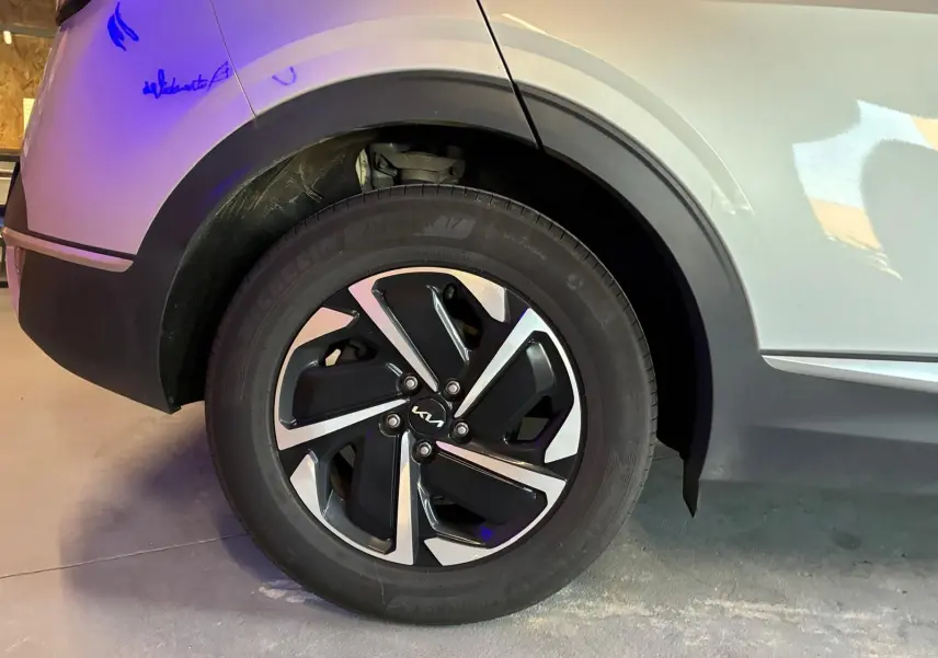 Gros plan sur la roue arrière droite grise d’un Kia Sportage 2024 hybride avec jante alliage bicolore distinctive.