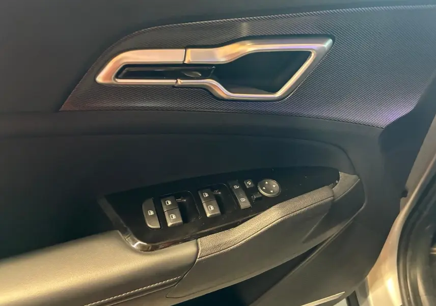 Poignée de porte intérieure et commandes des vitres côté conducteur du KIA Sportage gris hybride 2024, vue rapprochée.