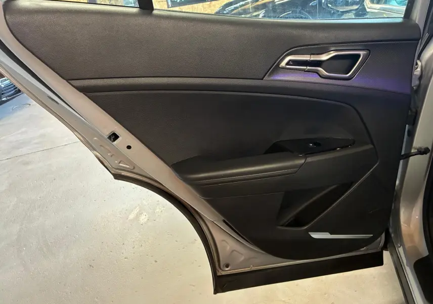 Vue intérieure de la porte arrière droite du Kia Sportage gris 2024, avec garniture noire et poignée argentée.