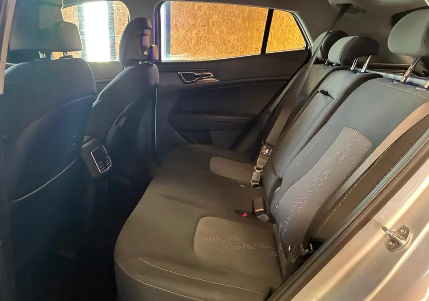 Vue intérieure côté droit sur les sièges arrière noirs du Kia Sportage hybride gris 2024, avec ceinture de sécurité visible.