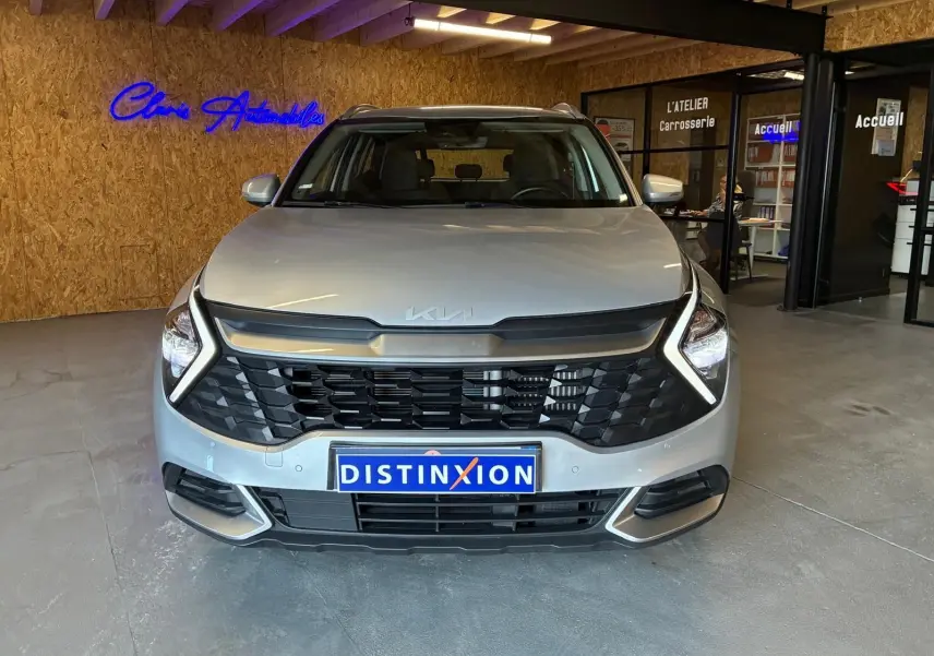 Vue frontale du KIA Sportage gris 2024 hybride avec calandre noire et éclairage LED en forme de boomerang.