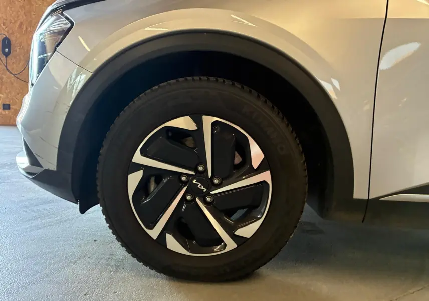Gros plan sur la roue avant gauche du KIA Sportage gris 2024, mettant en valeur la jante noire et argentée au design moderne.