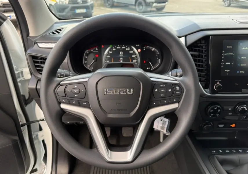 Vue intérieure centrée sur le volant multifonctions d'un Isuzu D-MAX blanc avec tableau de bord et écran tactile.