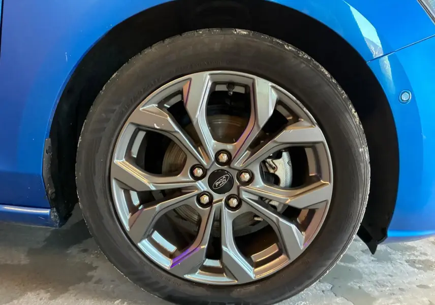Gros plan sur la roue avant droite d'une Ford Focus bleu 2024, mettant en valeur la jante alliage au design moderne.