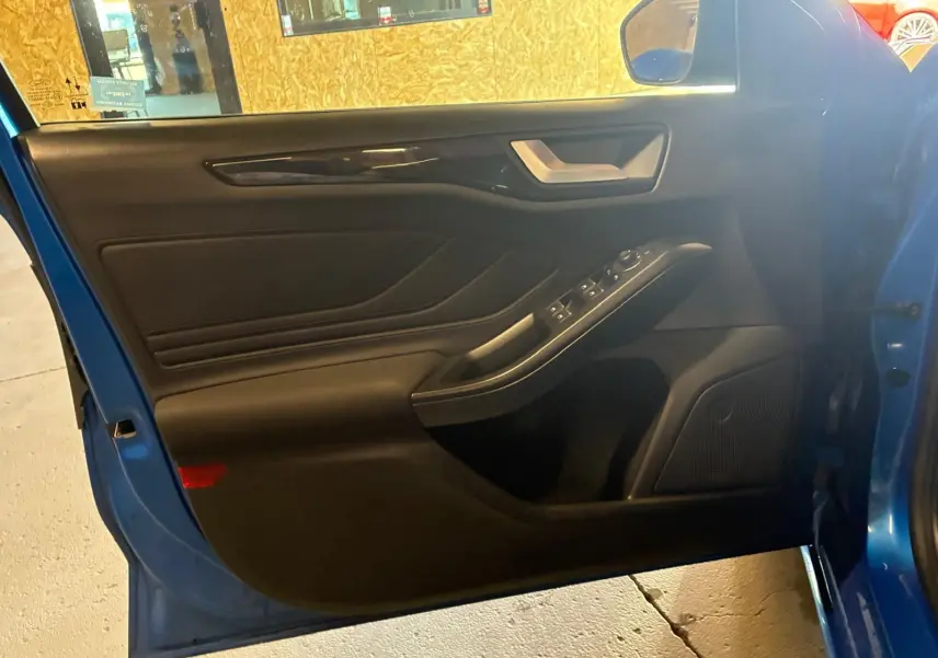 Vue intérieure de la porte avant gauche bleue de la Ford Focus 2024, avec commandes électriques et garniture noire.