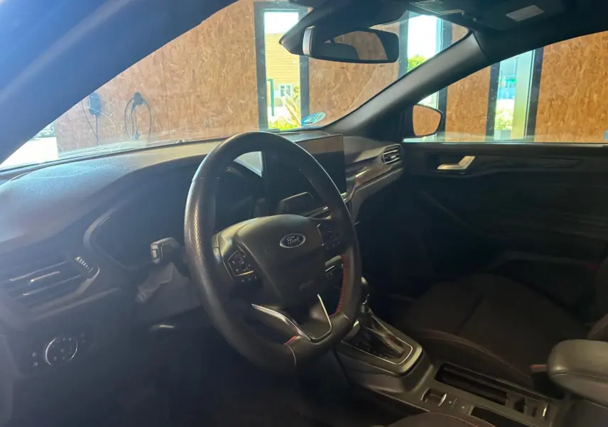 Vue intérieure côté conducteur de la Ford Focus 2024 bleu, volant multifonction et console centrale avec boîte automatique.