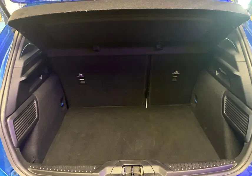 Vue intérieure du coffre ouvert d'une Ford Focus bleue 2024, montrant un espace de rangement propre et spacieux.