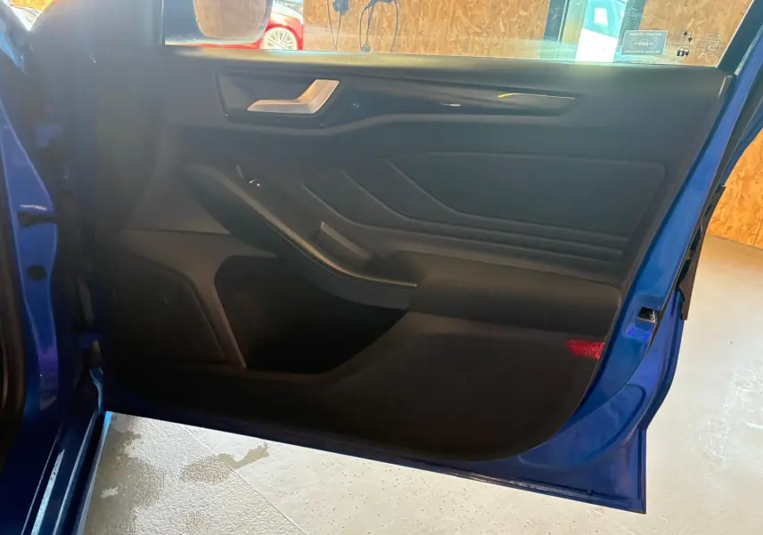 Vue intérieure de la porte avant gauche bleu de la Ford Focus 2024, avec garniture noire et poignée argentée.
