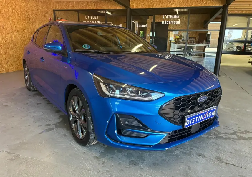 Ford Focus 2024 bleu en vue 3/4 avant droit, avec calandre noire hexagonale et phares LED distinctifs.