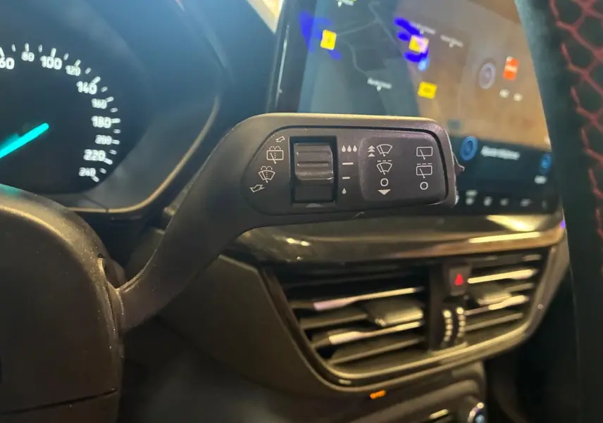 Gros plan sur la commande des essuie-glaces côté gauche dans l’habitacle noir d’une Ford Focus bleue 2024.