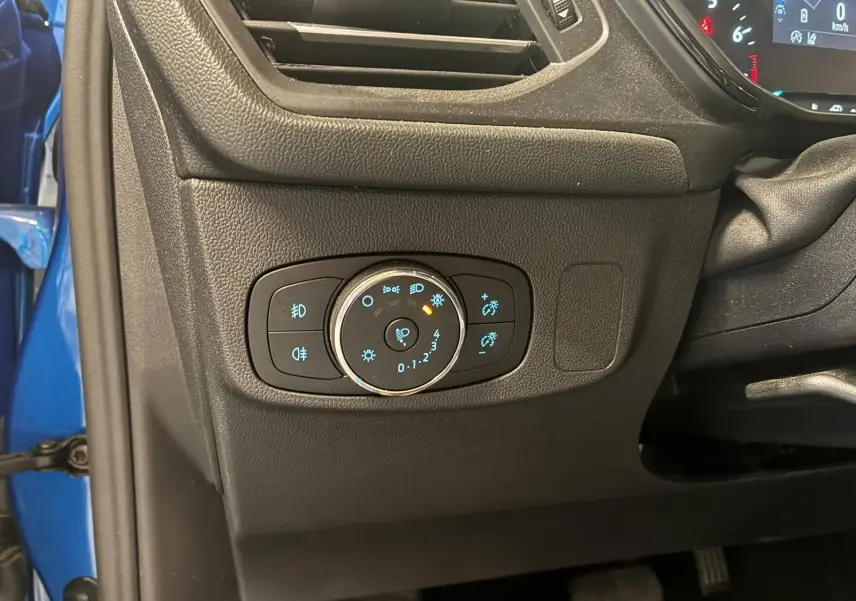 Détail du tableau de bord côté gauche d'une Ford Focus bleu 2024, avec commandes d'éclairage et ventilation visibles.