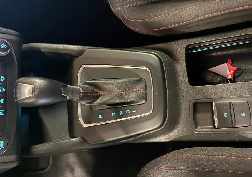 Vue intérieure centrée sur le levier de vitesses automatique noir avec surpiqûres rouges dans une Ford Focus bleue 2024.