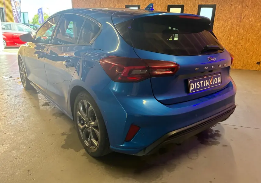 Vue 3/4 arrière droite d'une Ford Focus bleu 2024 avec finition ST Line et feux arrière LED distinctifs.