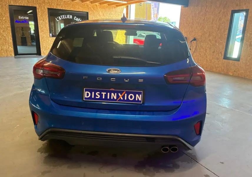 Vue arrière d'une Ford Focus bleue 2024, version ST Line avec double sortie d'échappement et vitres teintées.