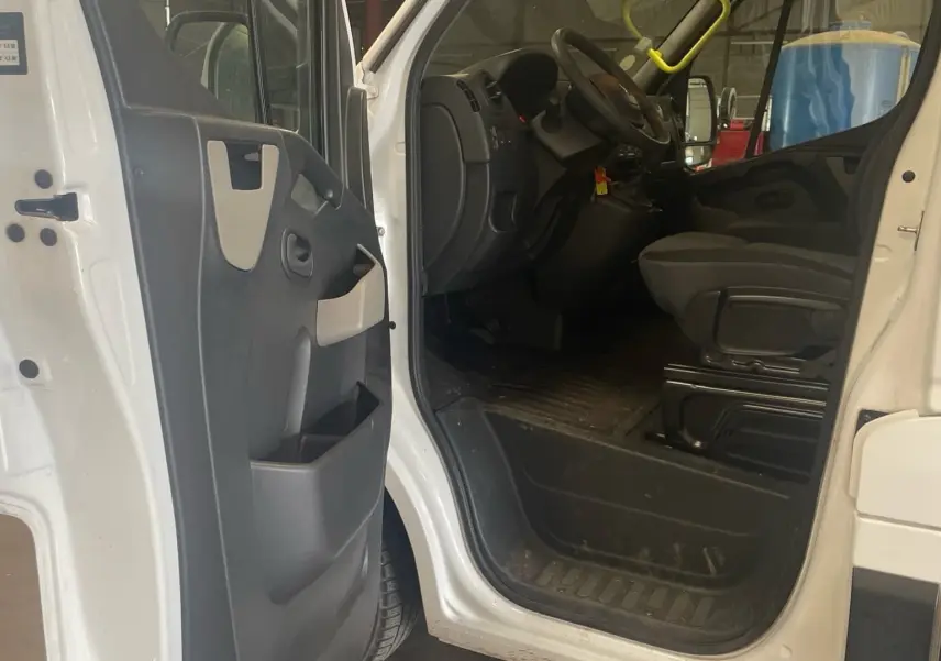 Vue intérieure côté conducteur du Renault Master blanc 2019 avec porte ouverte montrant le siège et le tableau de bord.