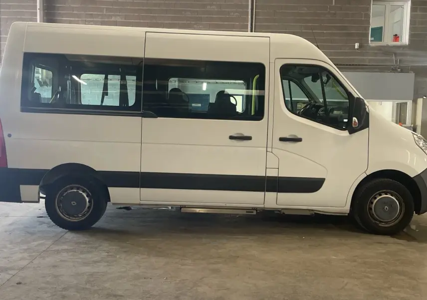 Profil droit d’un Renault Master blanc 2019 avec porte latérale coulissante et marchepied visible en intérieur d’atelier.