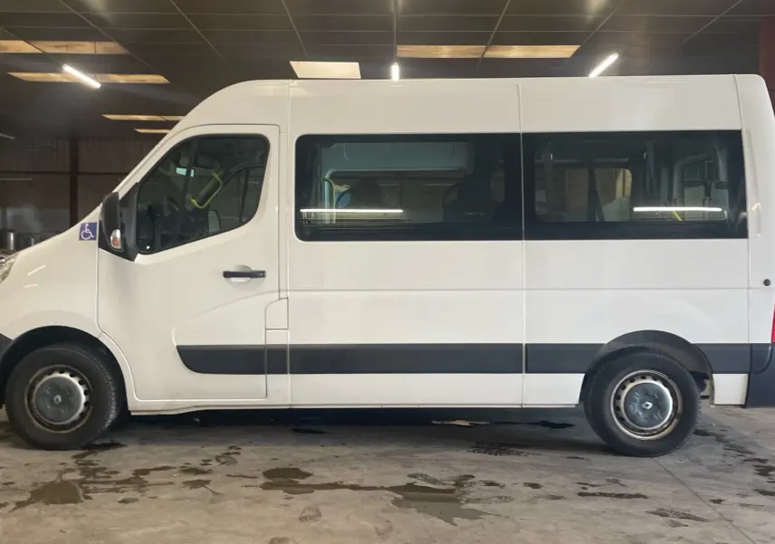 Profil latéral droit d’un Renault Master blanc TPMR 2019 avec rampe arrière et logo handicap visible près de la porte avant.