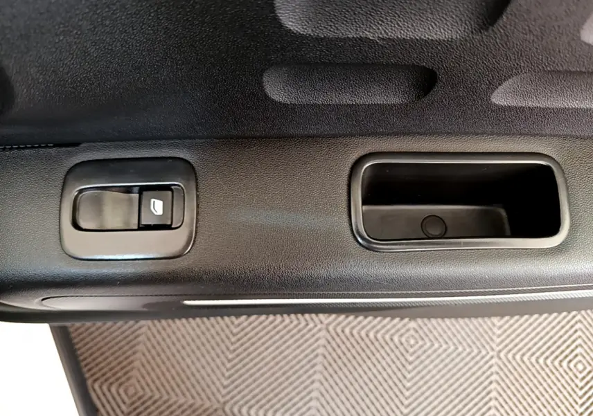 Gros plan sur la commande de lève-vitre et poignée intérieure noire côté gauche d'une Citroën C3 blanche 2019.