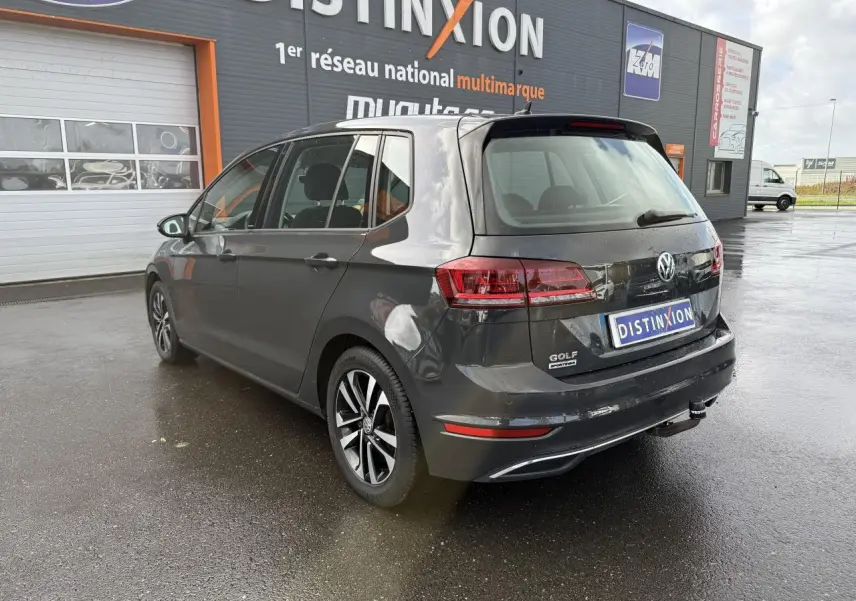 Volkswagen Golf Sportsvan gris Urano vue 3/4 arrière droit, avec jantes alliage et attelage visible.
