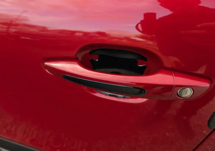 Poignée de porte rouge foncé avec insert noir sur une Citroën C4 2024 vue en gros plan.