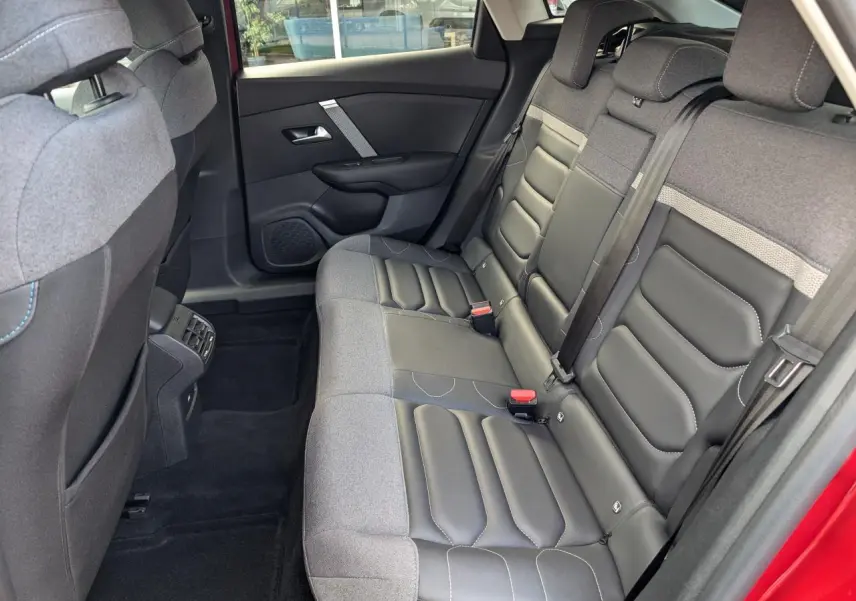 Vue intérieure côté droit de la banquette arrière en tissu gris et cuir noir du Citroën C4 rouge foncé 2024.