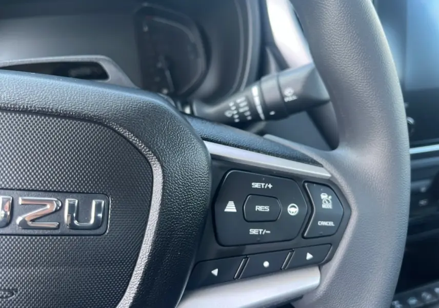Gros plan sur le volant multifonctions noir de l'Isuzu D-MAX 2026, mettant en valeur les commandes de régulateur de vitesse.