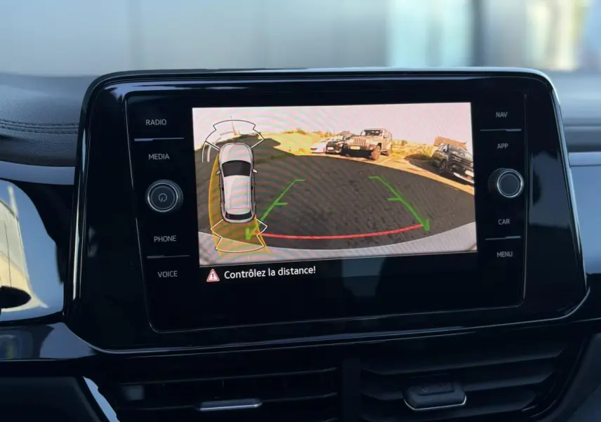 Écran central du Volkswagen T-Roc 2025 affichant la caméra de recul avec alertes de distance en intérieur noir brillant.