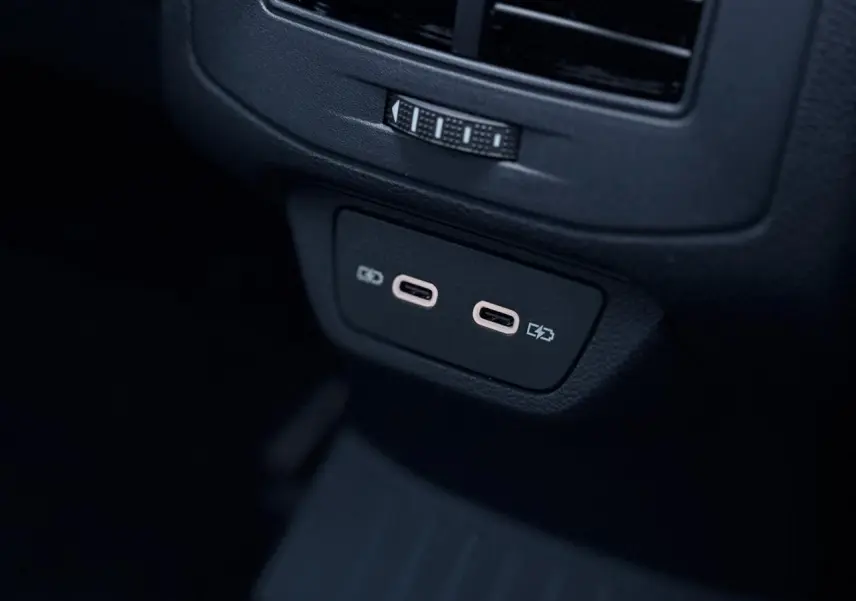 Prise USB-C double en gros plan à l'arrière d'un Volkswagen T-Roc 2025 gris Pyrite avec intérieur noir.