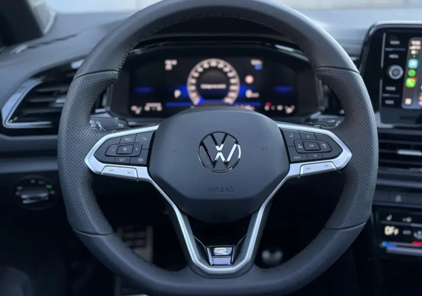 Volant sport noir avec logo VW R-Line au centre, vue frontale du poste de conduite du Volkswagen T-Roc 2025.