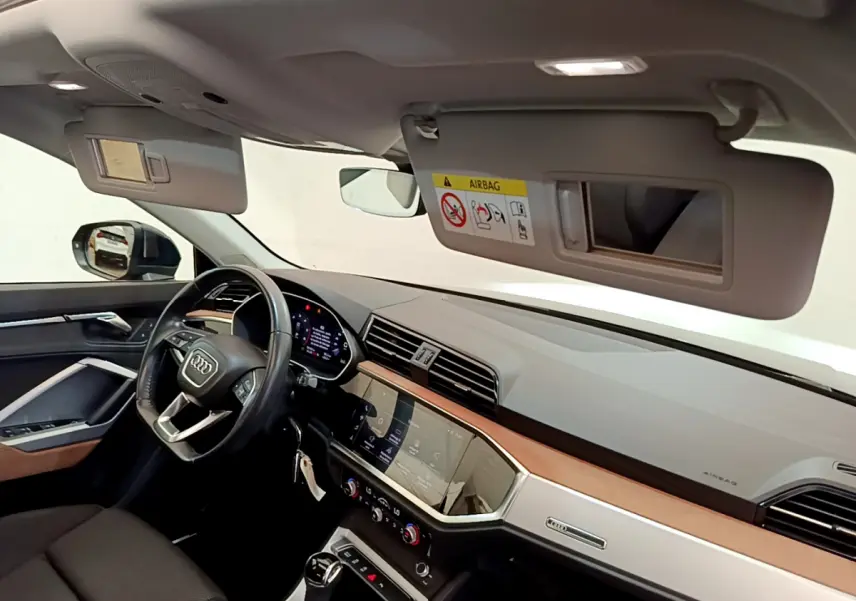 Intérieur de l'Audi Q3 35 TDI 2020 vu côté conducteur, tableau de bord moderne avec écran tactile et volant cuir noir.