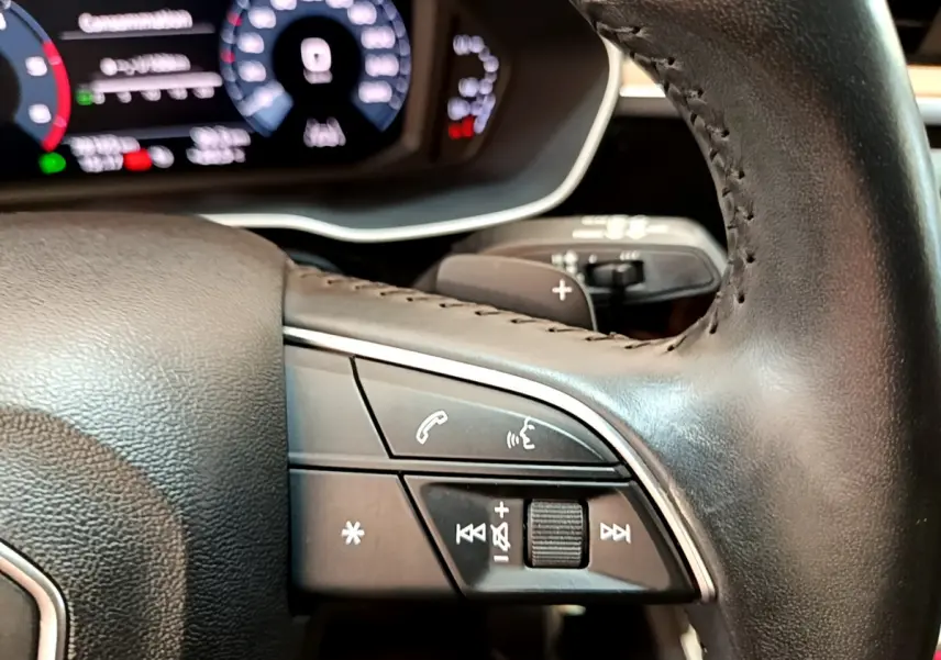 Gros plan sur les commandes multifonctions du volant cuir noir de l'Audi Q3 35 TDI 2020 avec tableau de bord numérique.