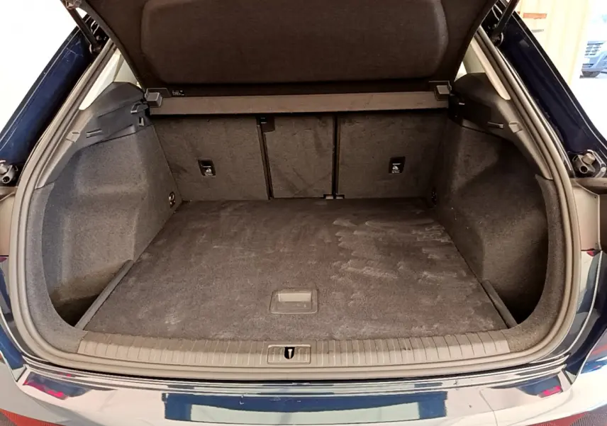 Coffre ouvert de l'Audi Q3 bleu 2020, vue arrière montrant l'espace de chargement vide et tapis gris.