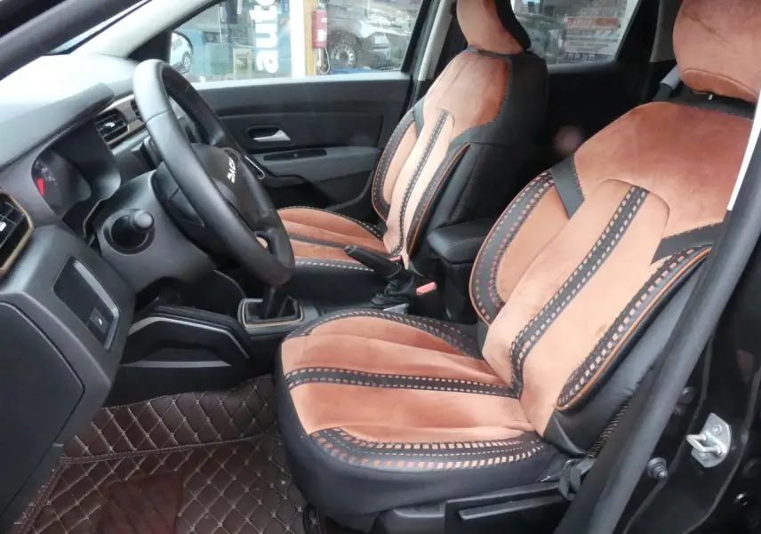 Intérieur du Dacia Duster 2023 version Extreme, vue côté conducteur, sièges marron et noir avec surpiqûres décoratives.