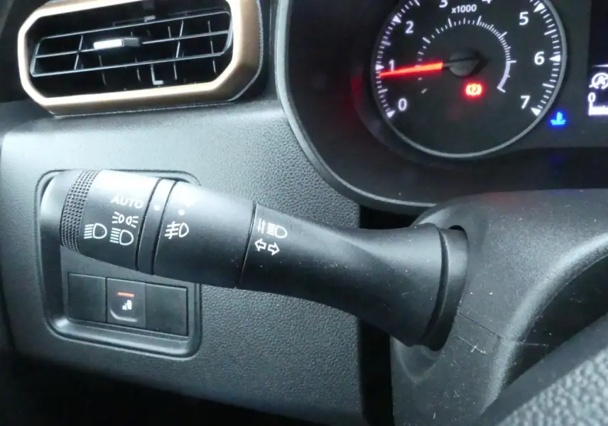 Gros plan sur la manette de commande d'éclairage et clignotants du tableau de bord noir du Dacia Duster 2023 finition Extreme.