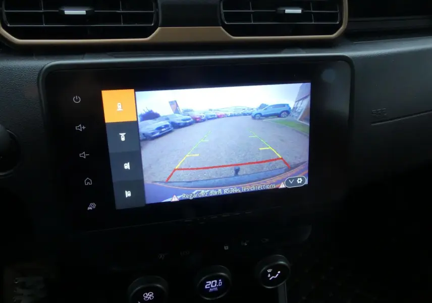 Écran central du Dacia Duster 2023 montrant la caméra de recul avec vue arrière sur un parking.