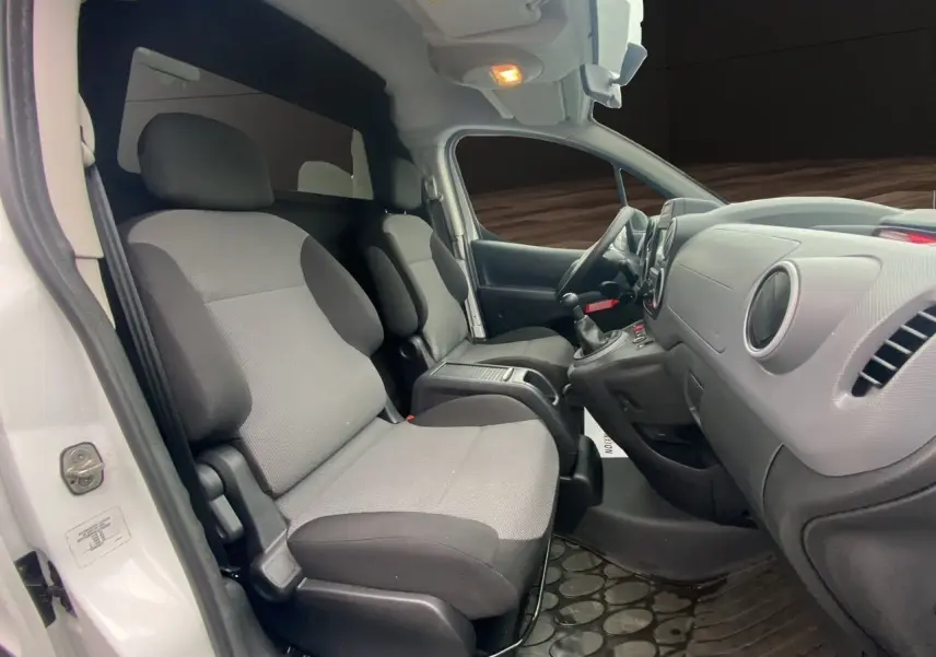 Vue intérieure côté conducteur du Citroën Berlingo blanc 2018, montrant les sièges avant et le tableau de bord simple.