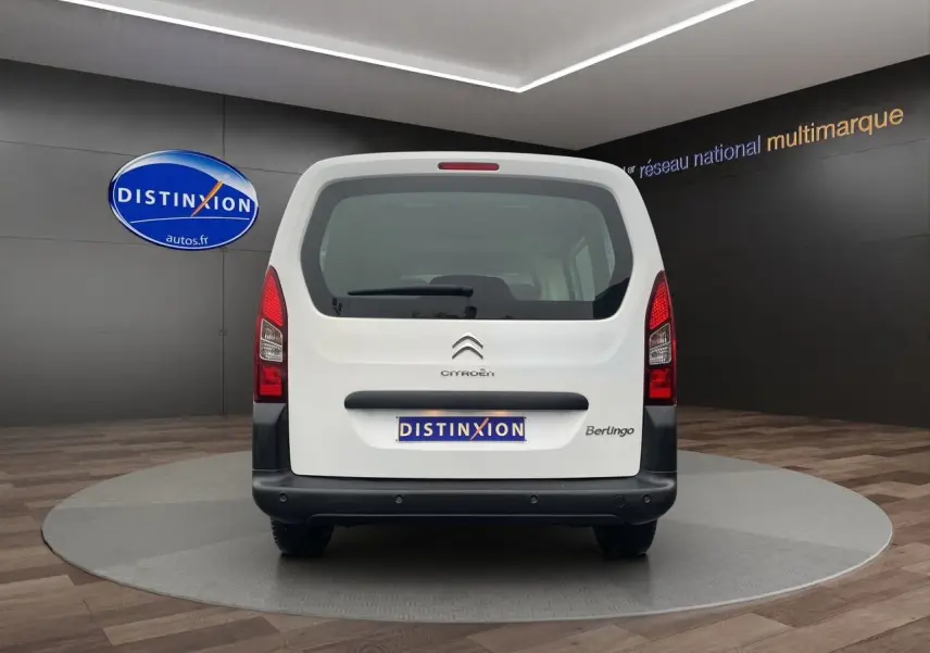 Vue arrière d'un Citroën Berlingo blanc 2018 avec hayon vitré et logo Distinxion visible en arrière-plan.